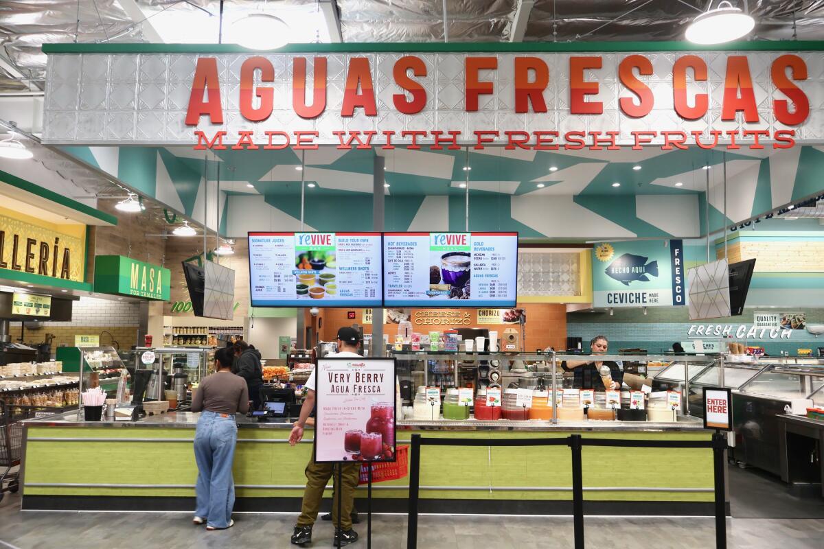 Employees of the Vallarta Supermarket in Carson serve aguas frescas and ice cream to customers on June 13.