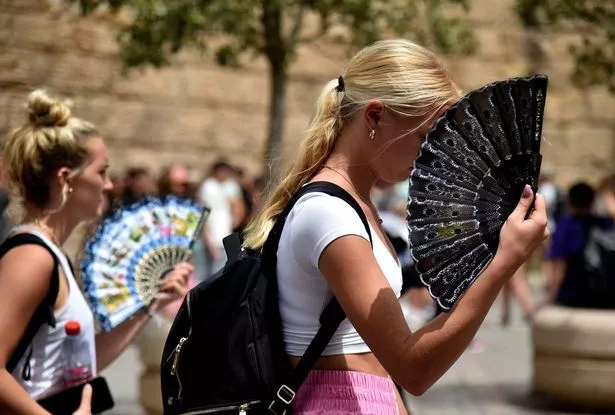 Two women use fans to fight the scorching heat 
