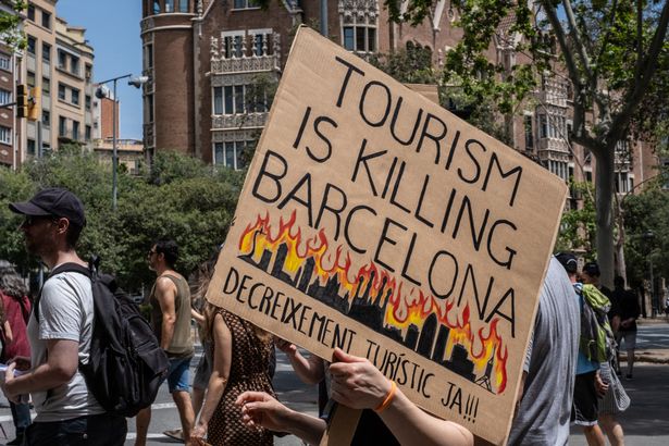 BARCELONA, SPAIN - JUNE 15:  Protestors march during an anti-tourism protest on June 15, 2025 in Barcelona, Spain. Activists against overtourism are holding protests across Spain, Portugal and Italy today as anger has been growing in southern Europe against excessive levels of tourism. They say high numbers of tourists flocking to these countries are forcing locals out of affordable accommodation, pushing up living costs and clogging up city centres. (Photo by Paroma Basu/Getty Images)