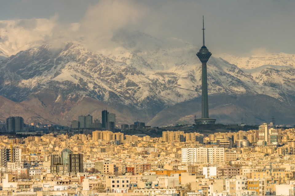Tehran skyline with Milad Tower and snow-capped mountains in the background.