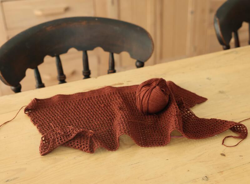 A brown knitted work rests on a table 