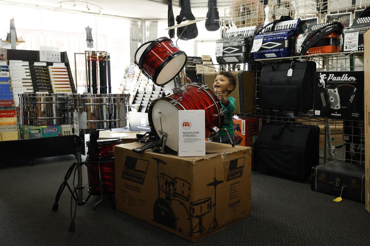 Joey Loya, 3, an aspiring drummer, looks over a small drum kit at Cassell's Music