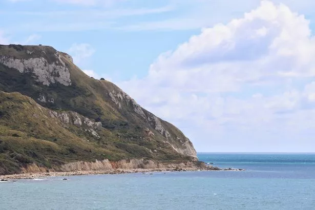 The rolling cliffs of the Jurassic coast under fluffy white clouds.
