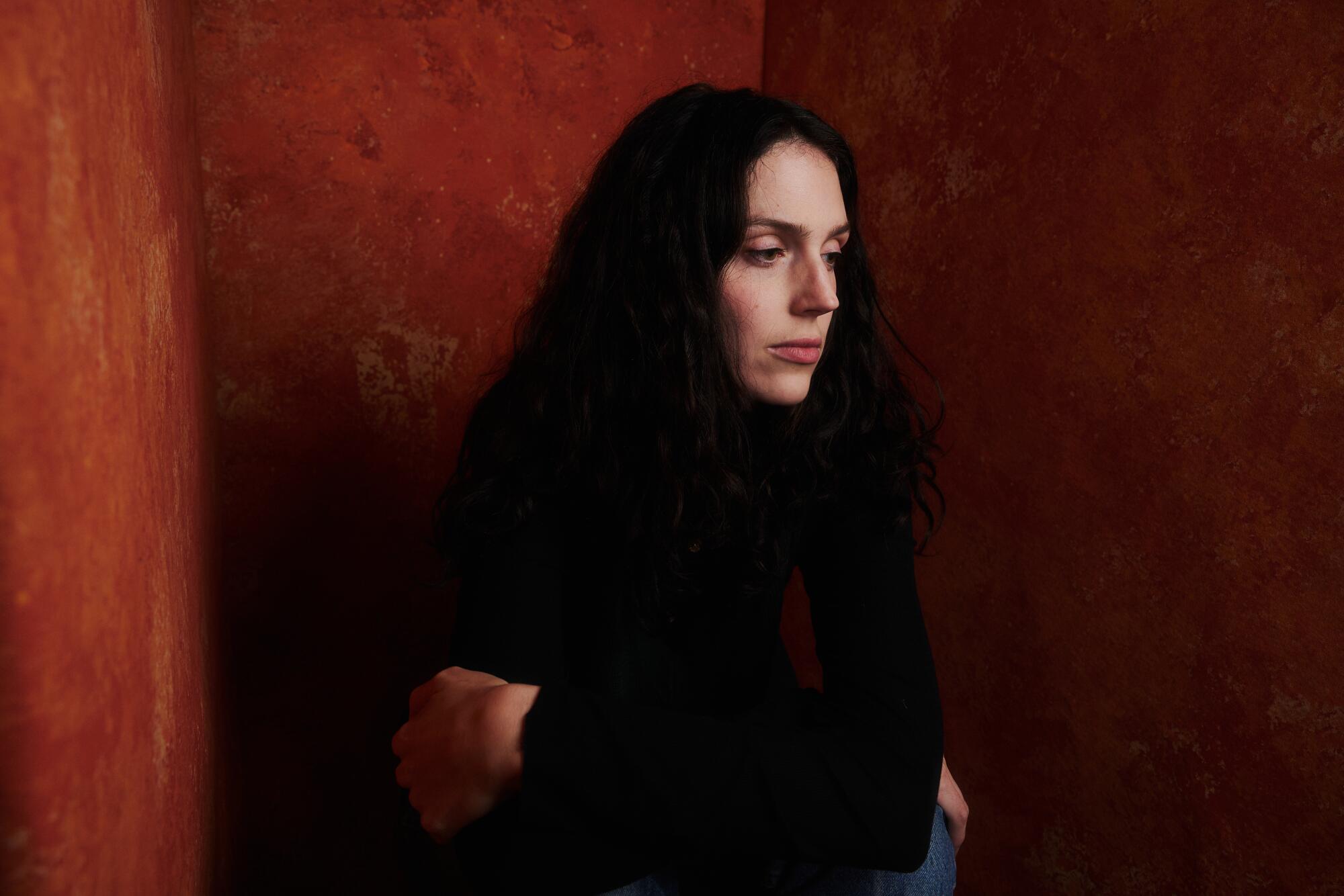 A woman in a dark top looks off to the side.