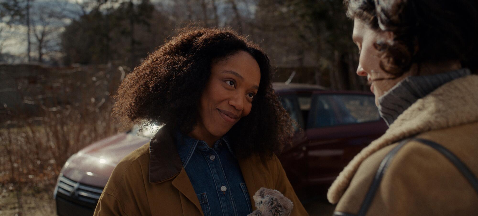 Two women smile at each other on the doorstep.