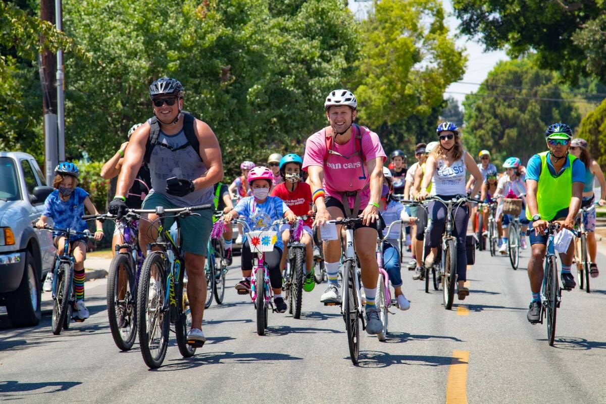 Large group of cyclists peddling on street through Culver City.