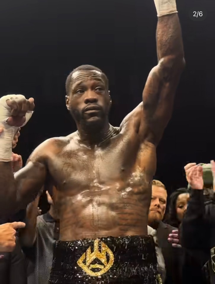 Boxer raising his arm in victory, wearing a championship belt.