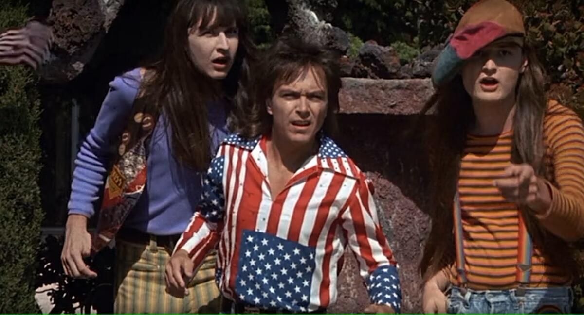 A man in an American flag shirt looks at something with curiosity.
