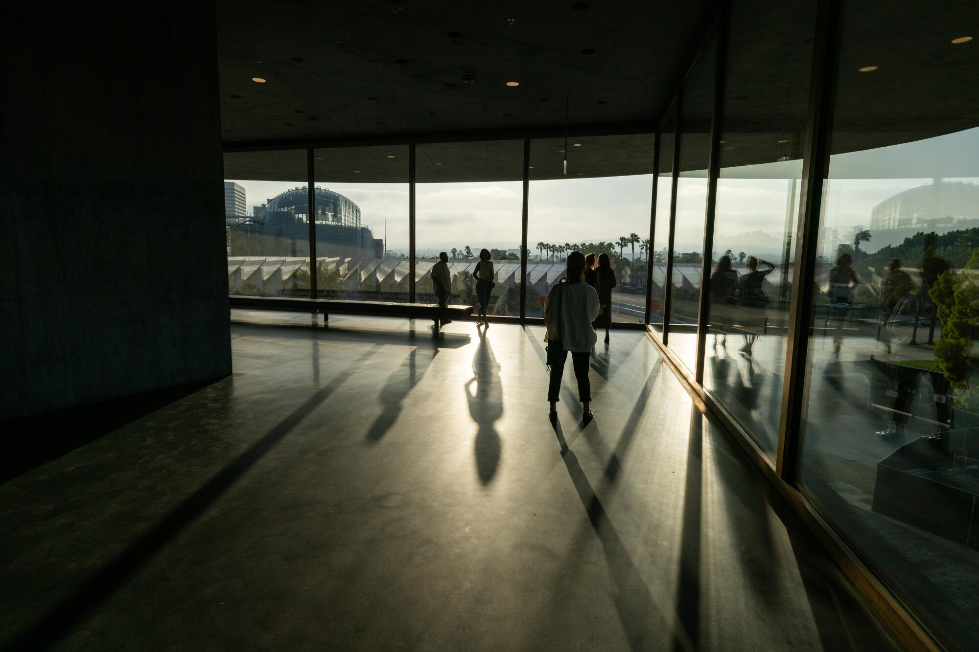Guests touring the new LACMA building cast long shadows as the sun sets.