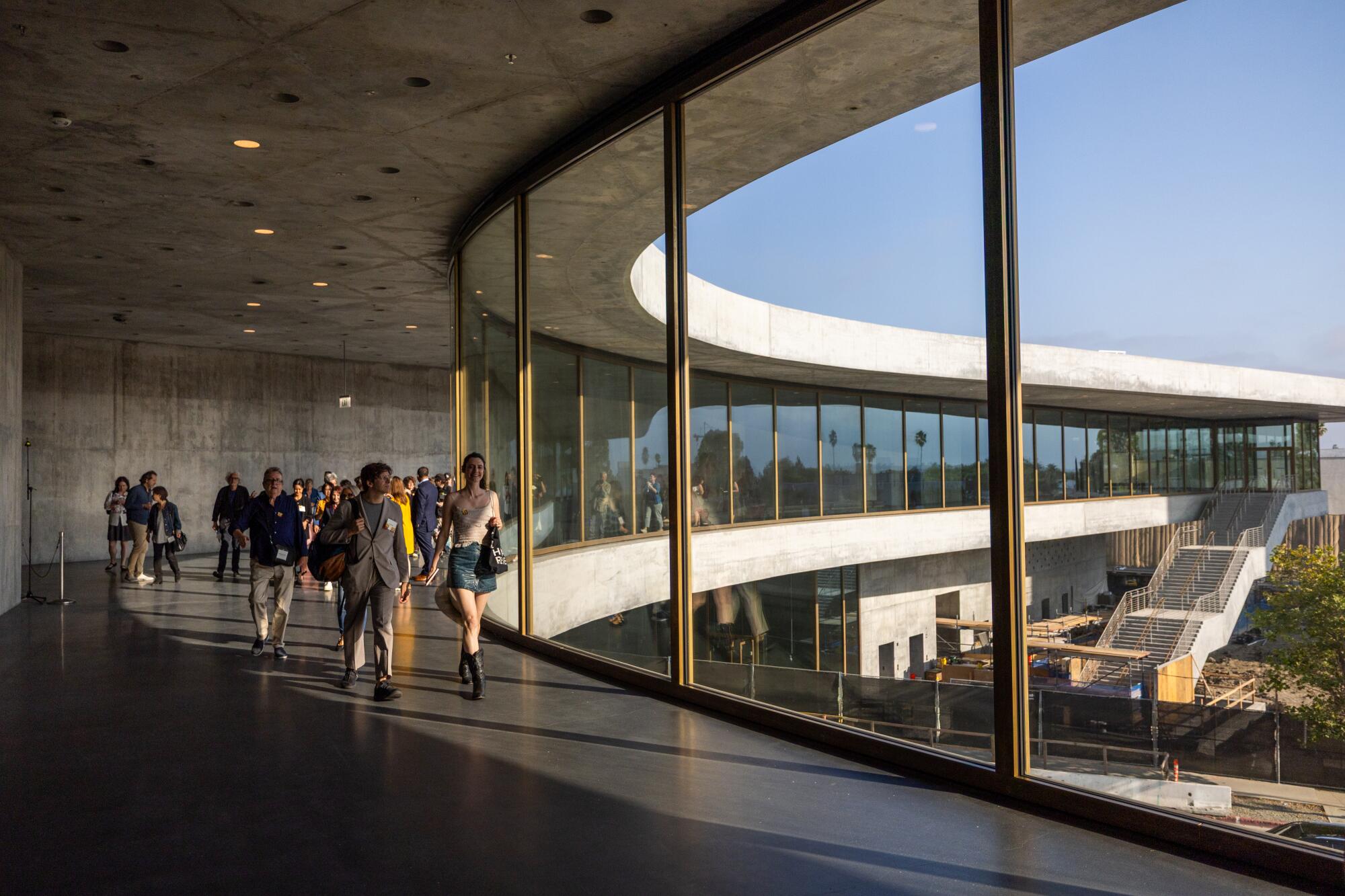 Guests at a preview inside the unfinished new LACMA building walk along its long expanse of glass.
