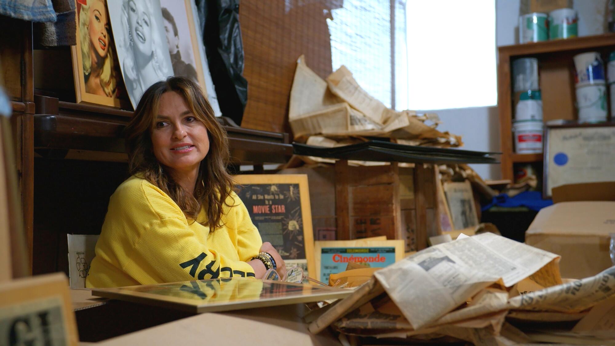 A woman sits surrounded by boxes inside a storage unit