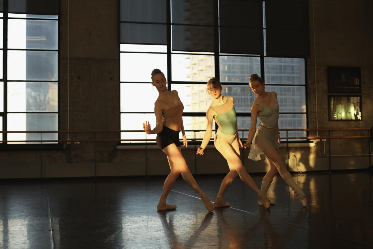 Claire, Nicole and Emma Von Enck, all with their hair in buns, rehearse ballet in a dance studio.
