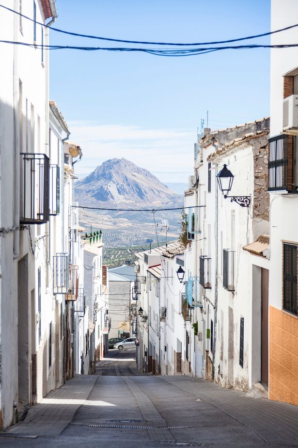 Image of narrow street in Albanchez with white facades, with Sierra Magina in the distance