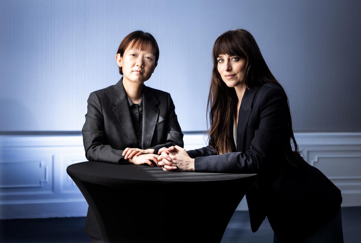 Two women in blazers pose next to each other at a table