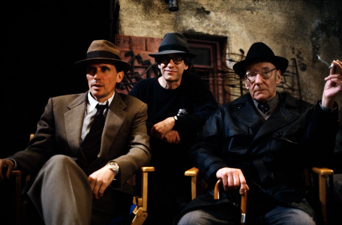Three men wearing fedoras on a movie set.