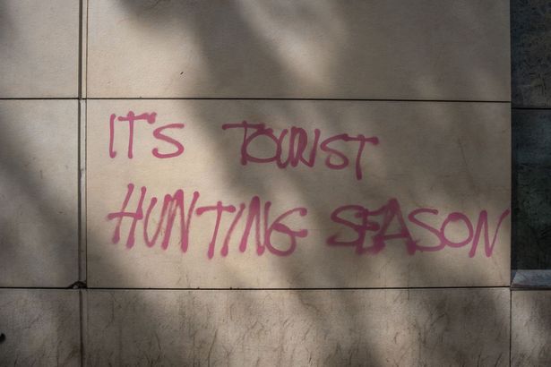 BARCELONA, CATALONIA, SPAIN - 2024/06/09: The political slogan It's tourist hunting season is seen painted on the wall of a building on Las Ramblas in Barcelona. Anti-tourist graffiti has appeared in central Barcelona as part of a protest movement reflecting the frustrations of locals who believe there are too many tourists visiting the city. One of Europe's most popular tourist destinations, Barcelona is struggling to find a balance between the economic benefits of mass tourism and its impact on local communities. (Photo by Paco Freire/SOPA Images/LightRocket via Getty Images)