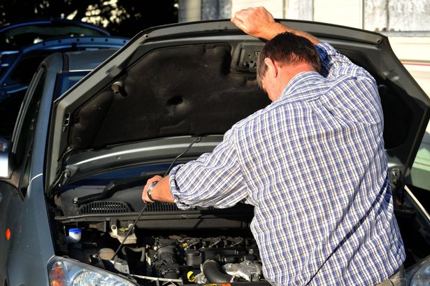 A man looking in a car engine