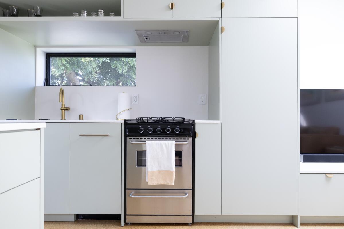 A tiny kitchen with pale green cabinets 