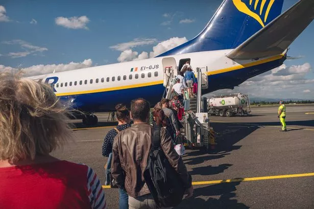 People walk to board a Ryanair plane heading to Porto in Portugal on the runway of Carcassonne airport in Aude, France