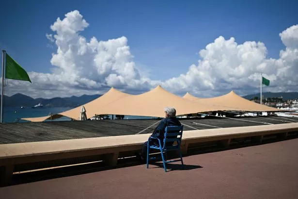 A sunbather relaxes on public chairs along the Boulevard de la Croisette, on the opening day of the 78th edition of the Cannes Film Festival in Cannes, southern France, on May 13, 2025. (Photo by Julie SEBADELHA / AFP) (Photo by JULIE SEBADELHA/AFP via Getty Images)