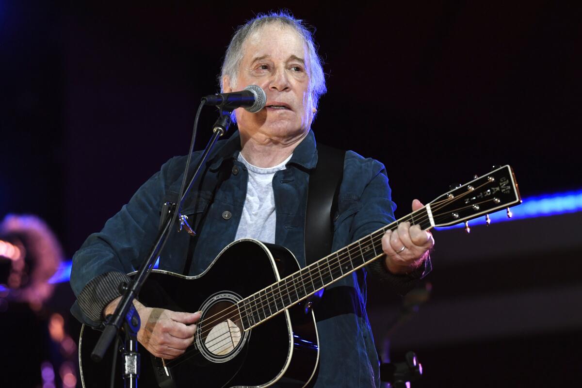A older man at a microphone playing guitar.
