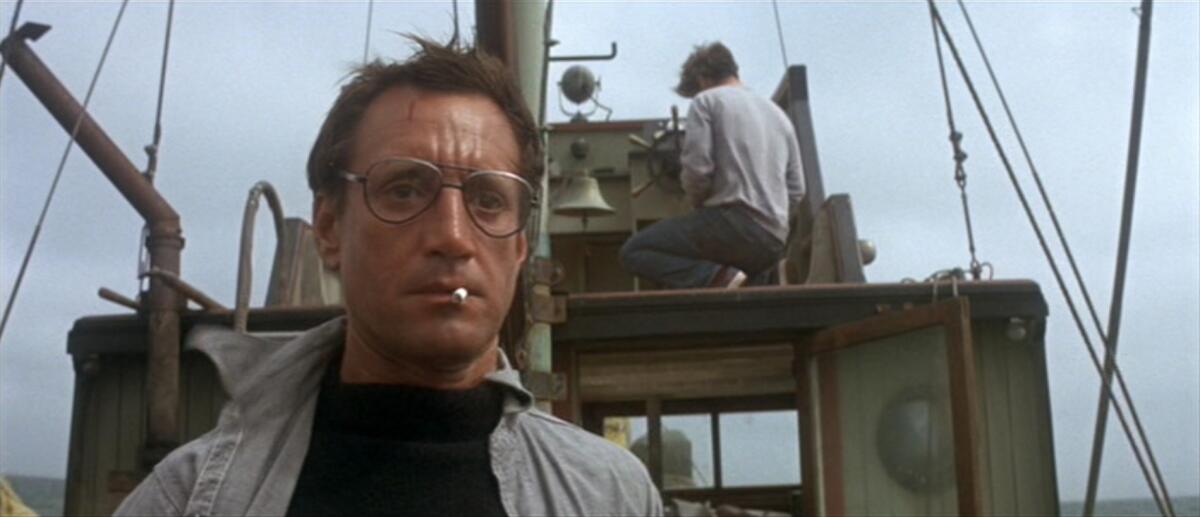 A man on the deck of a boat looks nervously at the water.