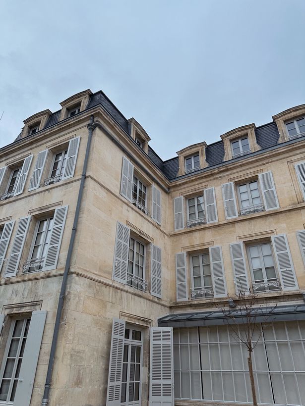 A photo of the side of a grand French building with white sandstone.