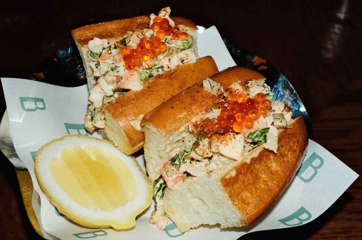 Two halves of an ikura-topped shrimp roll garnished with lemon cheek at Bar Benjamin.