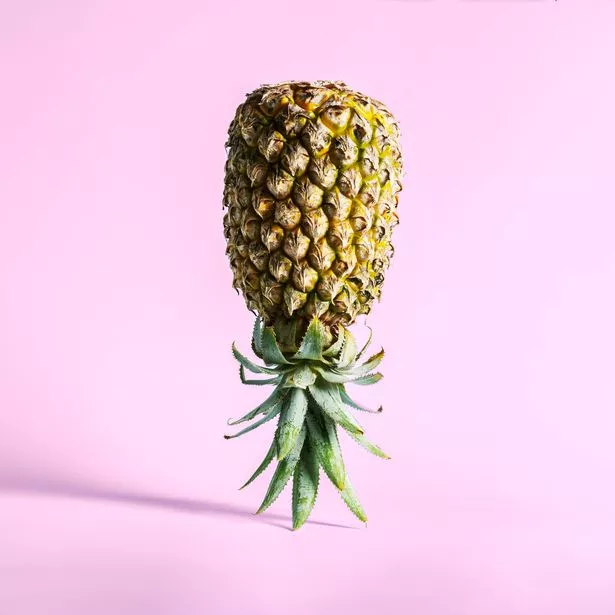 Inverted pineapple stands on a purple background