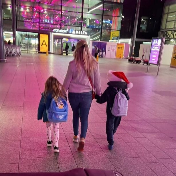 Anna Williamson, walking with her two children, whilst holding there hands, towards an airport.