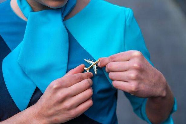 Flight attendant pinning a badge on her lapel