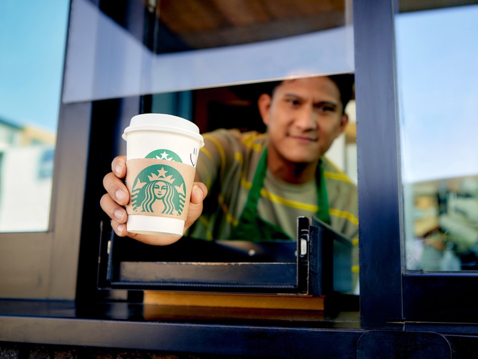 Starbucks barista handing over a coffee.
