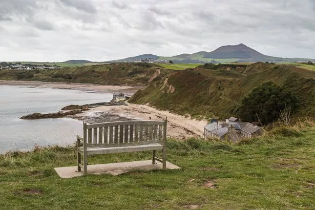 A bench overlooking the boats in the rocky cliffs of Porthdinllae