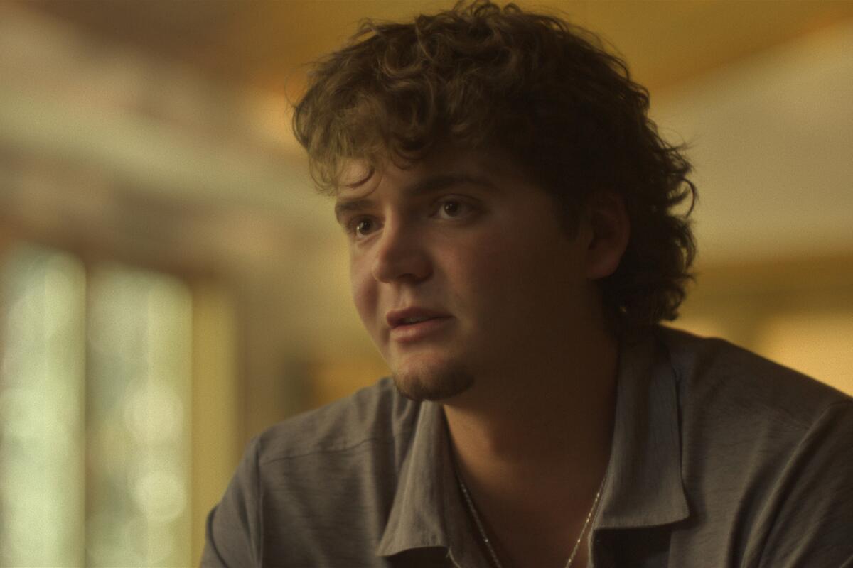 A man with short curly hair leaning forward.