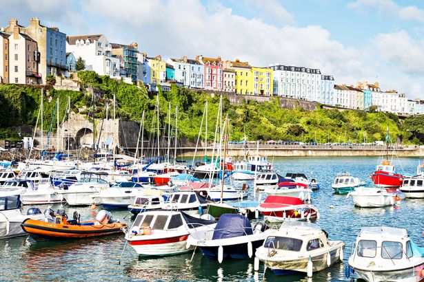 Tenby harbour at high tide with mooring boats and iconic colourful terraced houses