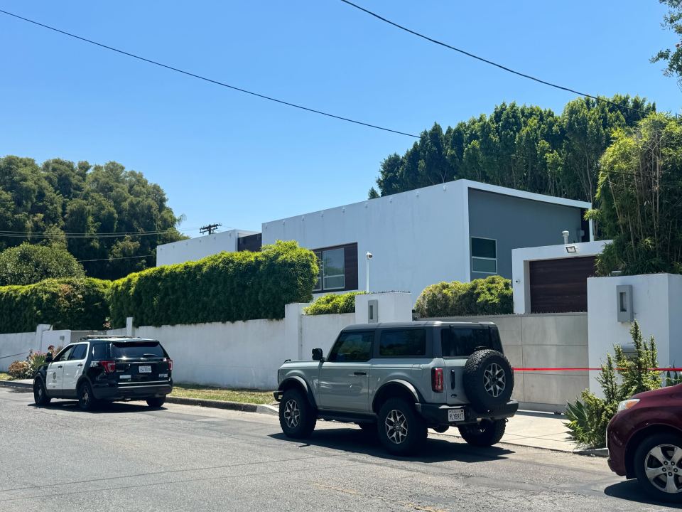 Crime scene outside a house with police vehicles.