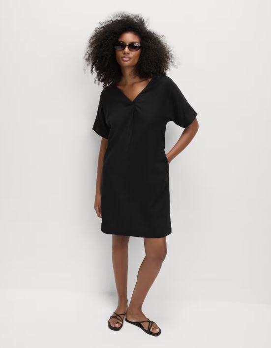 Model wearing a black linen dress and sandals.