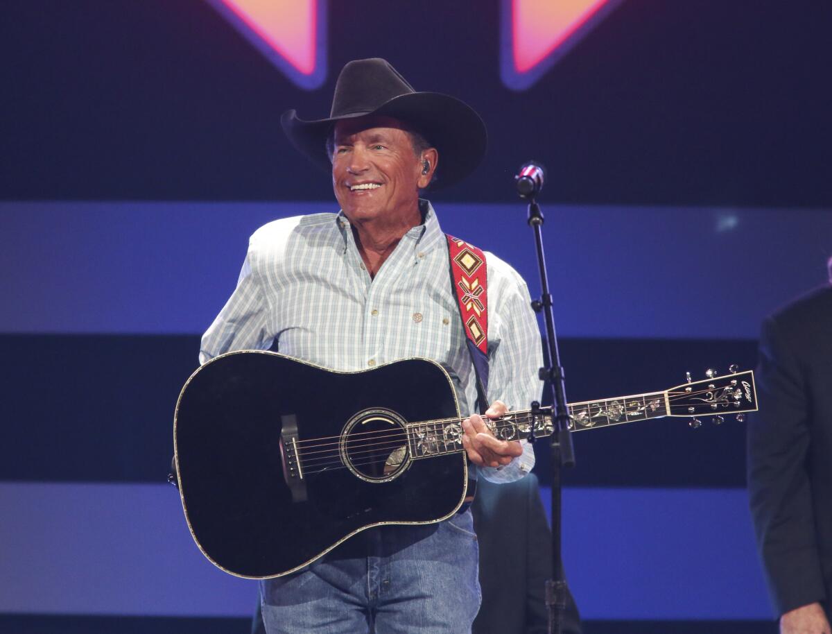 A man in a black cowboy hat with a guitar..