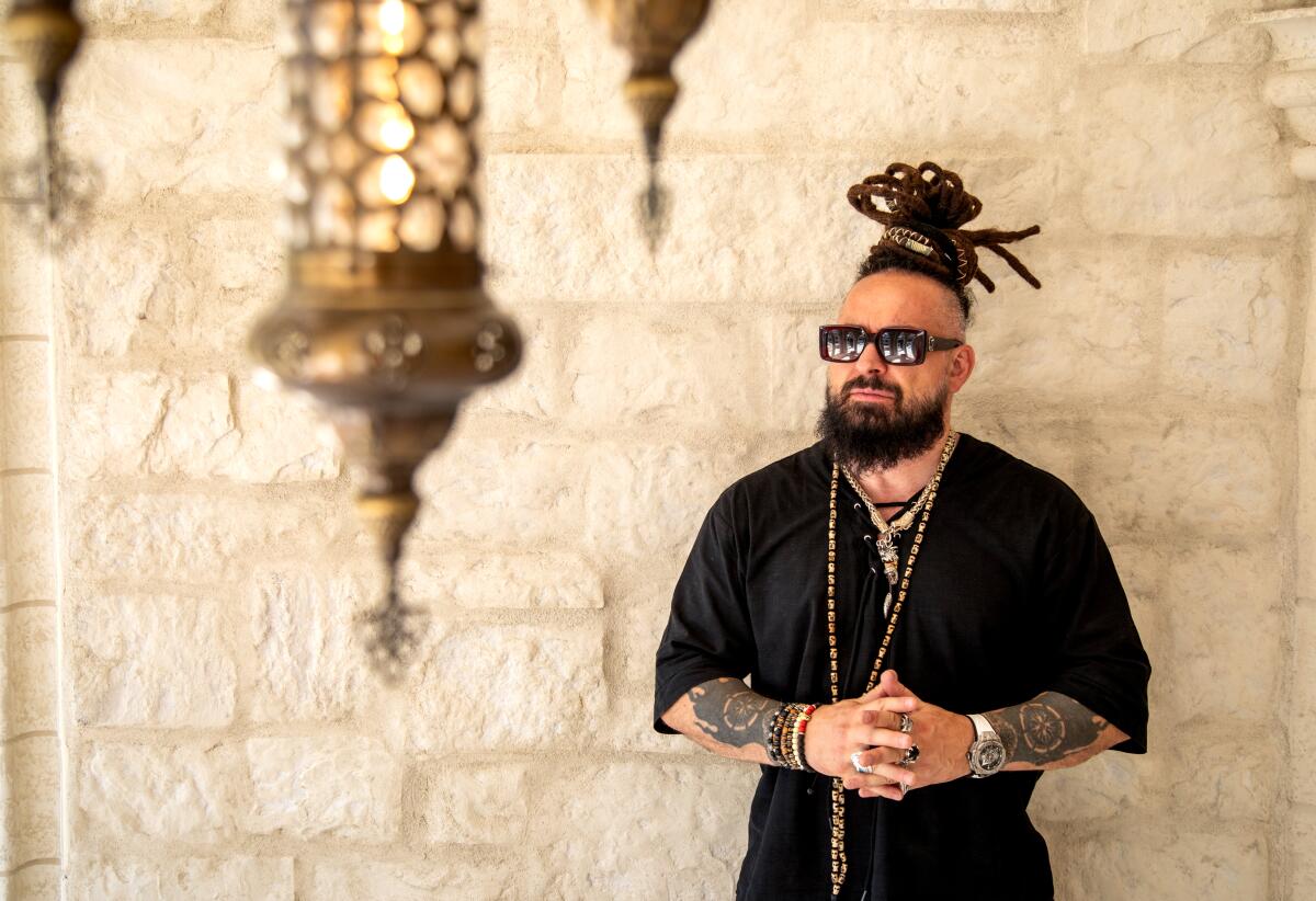 Man with dreadlocks and sunglasses standing in a castle under a row of Turkish lamps