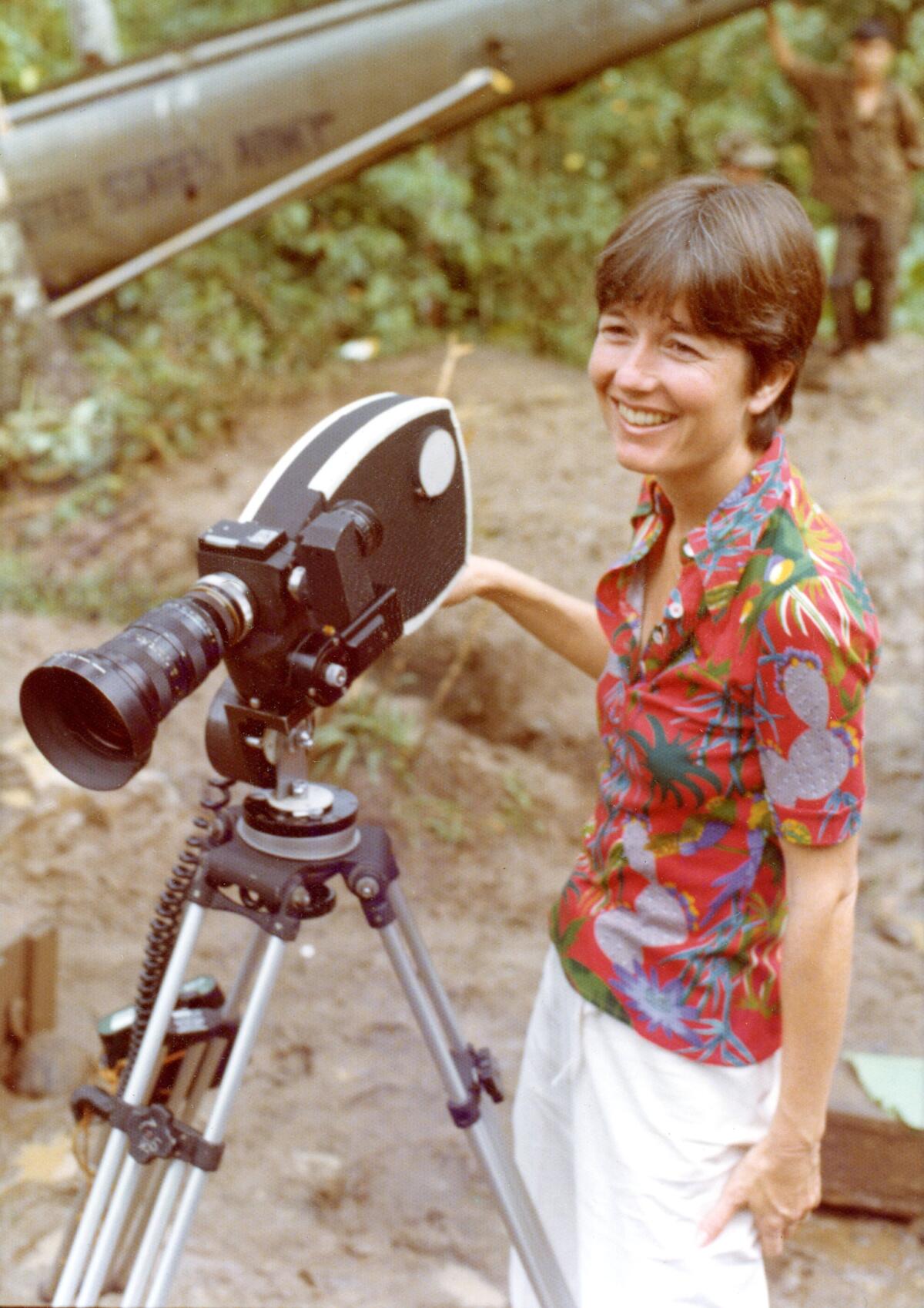 A woman in a red print top smiles at a camera.