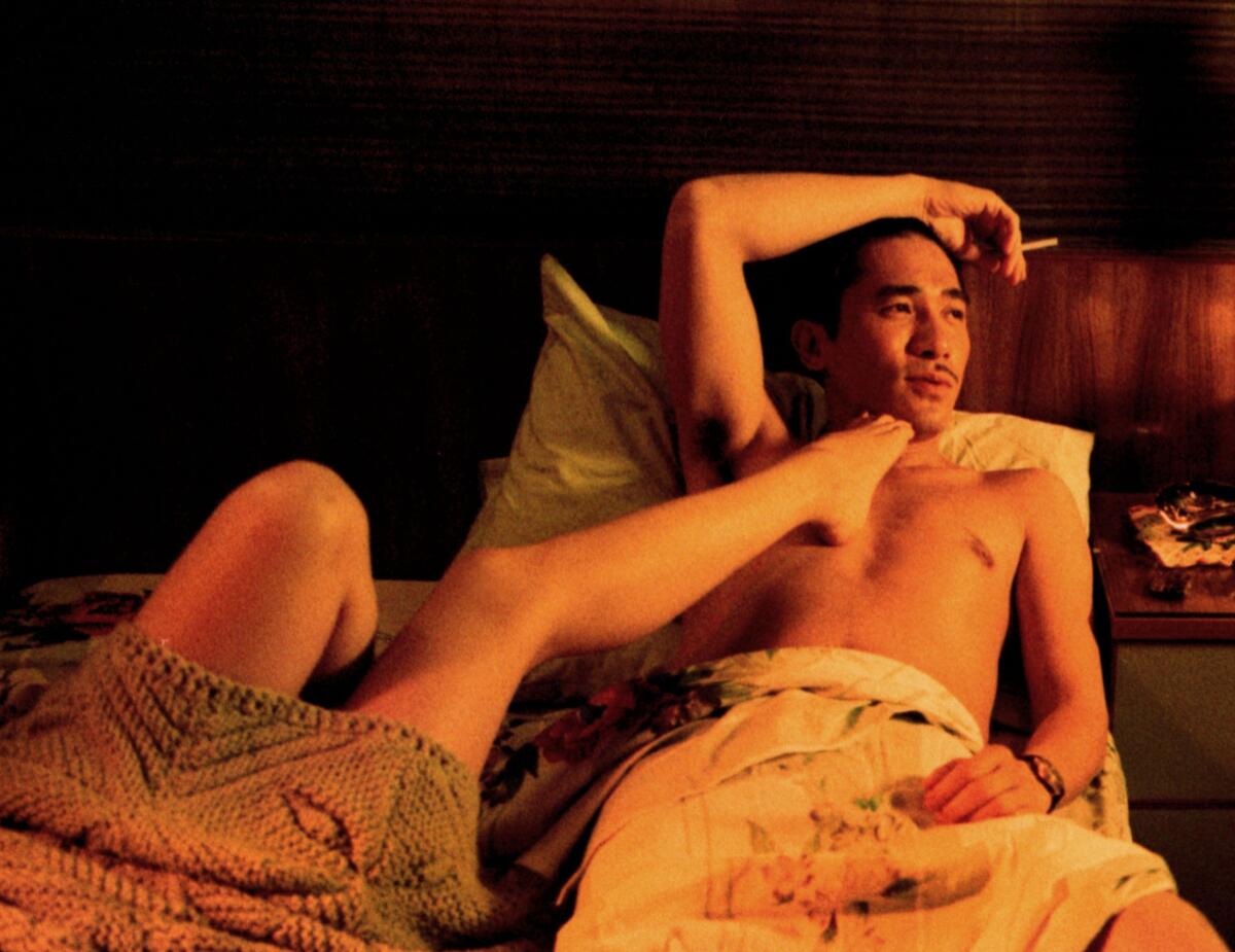 A man lays in bed, a woman's foot caressing his chest.