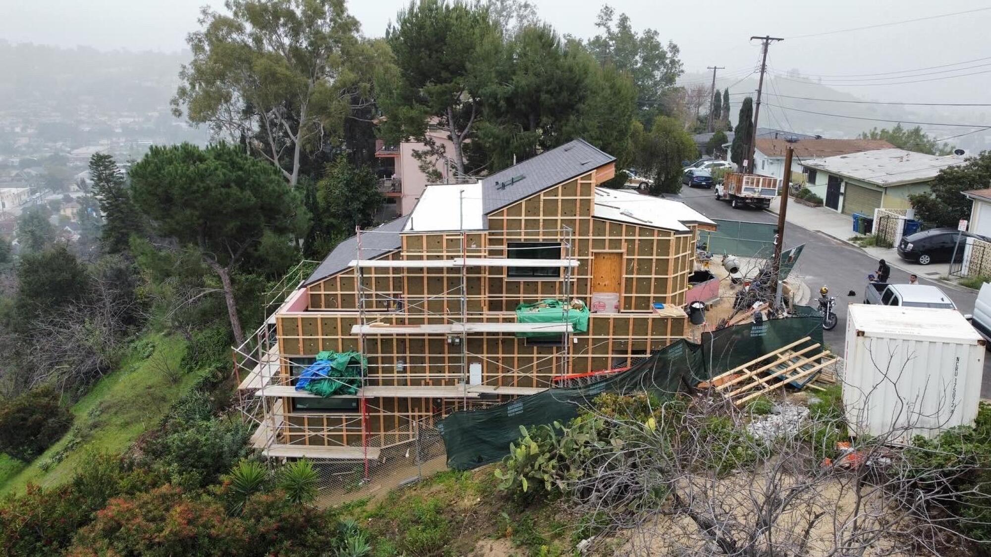 A framed house with a tilted roofline on a hillside lot 
