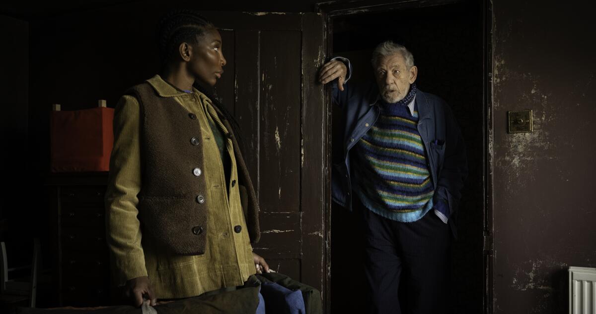 A man leaning in a doorway while a woman watches