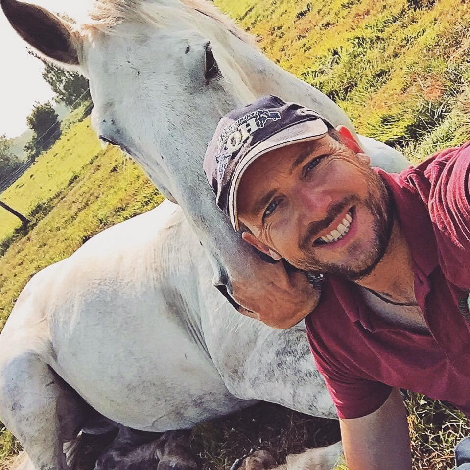 A man hugging a white horse.