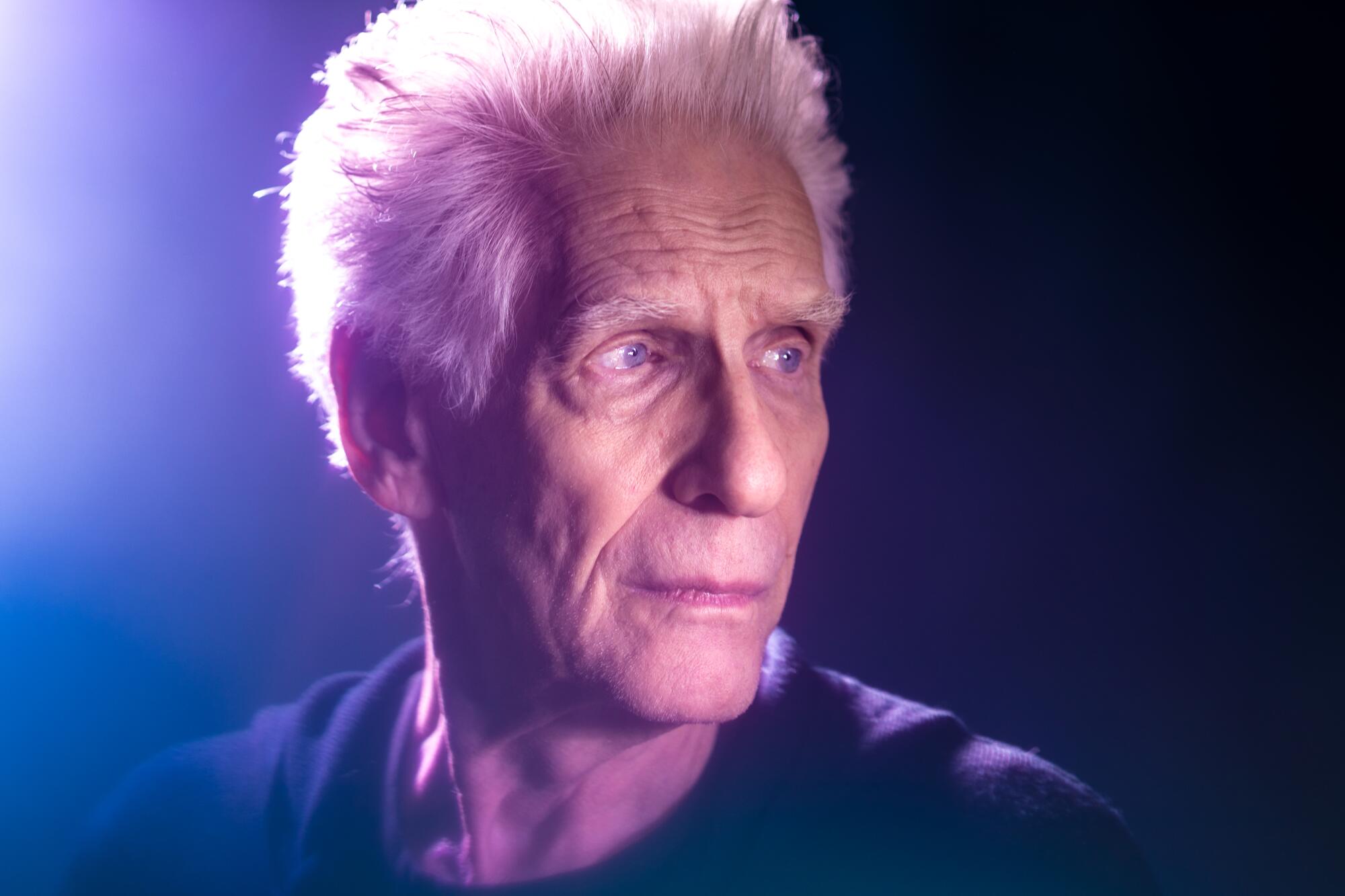 A man with gray hair looks off to the side.