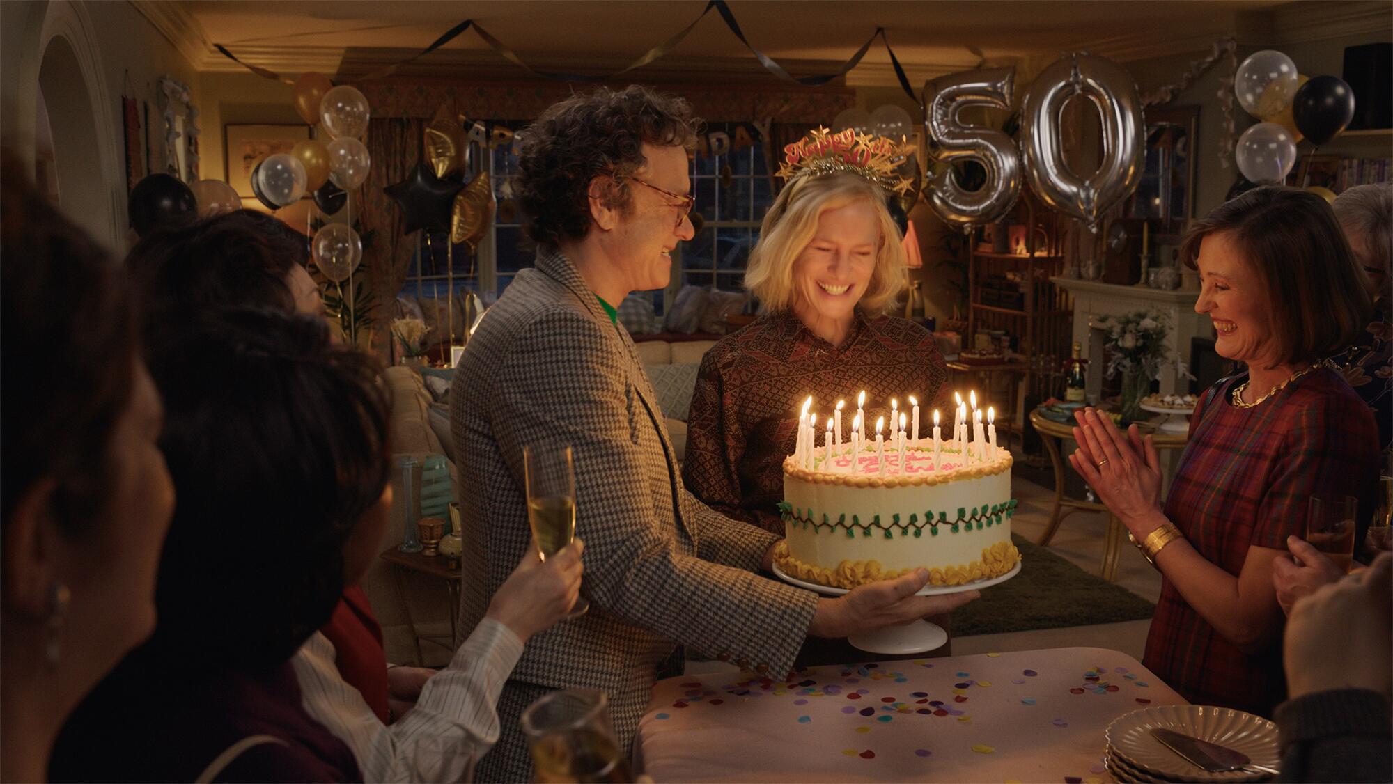 A man and a woman celebrate at a birthday party in a living room.