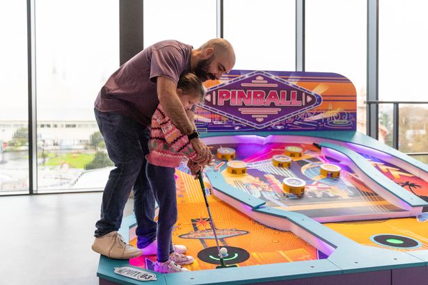 A man and child putting in an indoor mini golf 