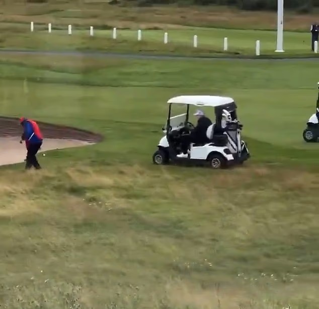 A golf caddy surreptitiously dropping a golf ball onto the green.
