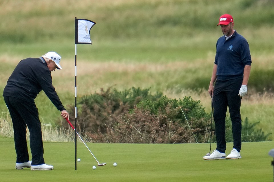 Donald Trump putting on a golf green, with another golfer watching.
