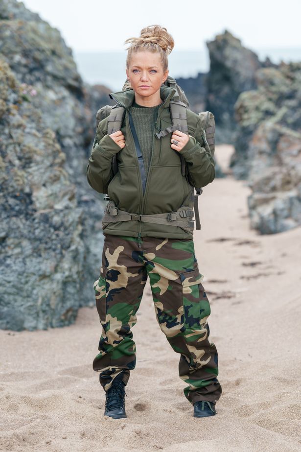 Hannah Spearritt, in green camouflage attire, stood on a beach.
